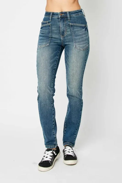Woman wearing high-rise blue denim jeans with front pockets and black sneakers