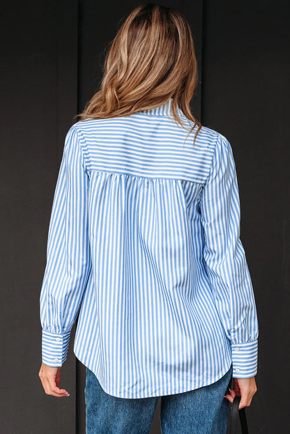 Woman wearing a blue and white striped long sleeve button-up shirt and jeans, shown from the back.