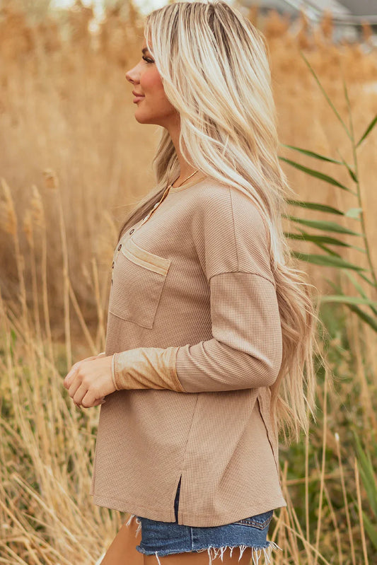 Woman wearing a beige waffle knit henley top with chest pocket and denim shorts outdoors