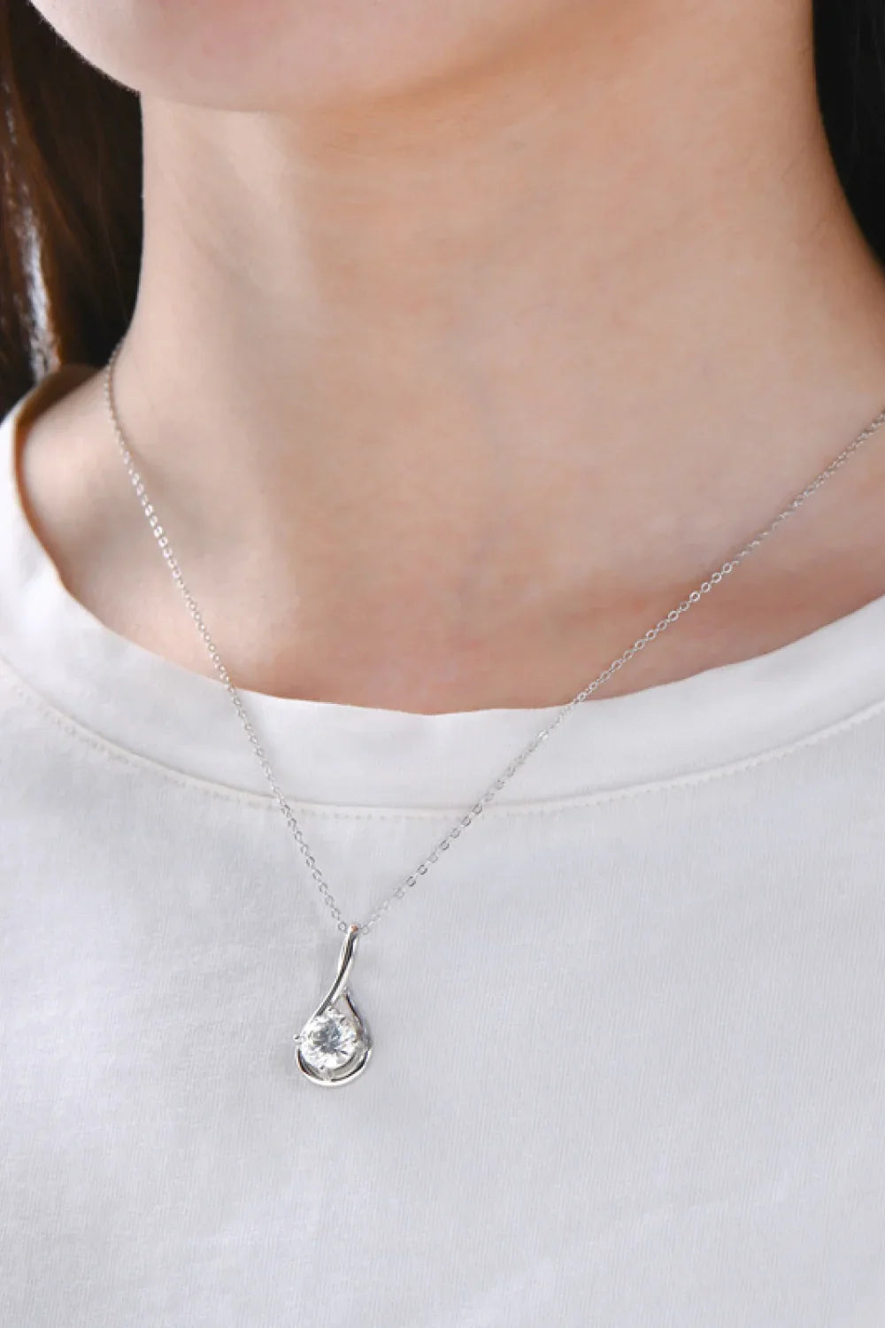Minimalist silver pendant necklace with teardrop design and clear gemstone on model