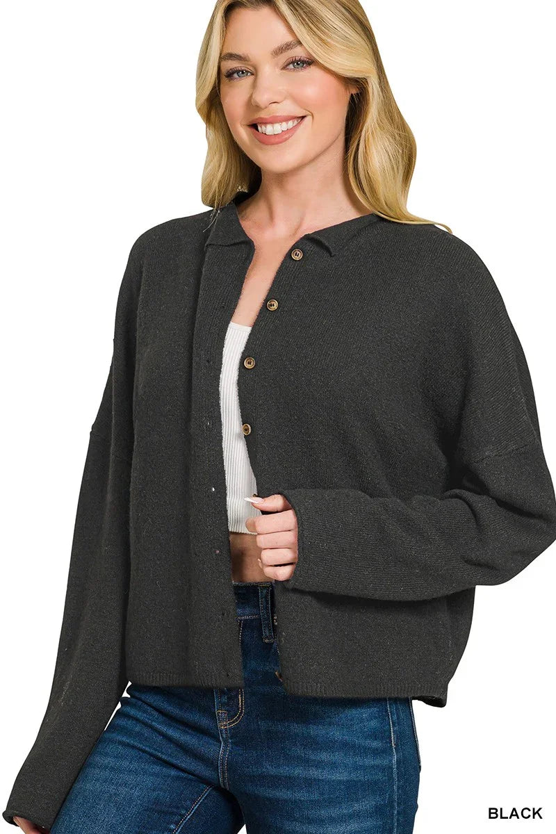 Woman wearing a black button-up cardigan over a white ribbed top and blue jeans