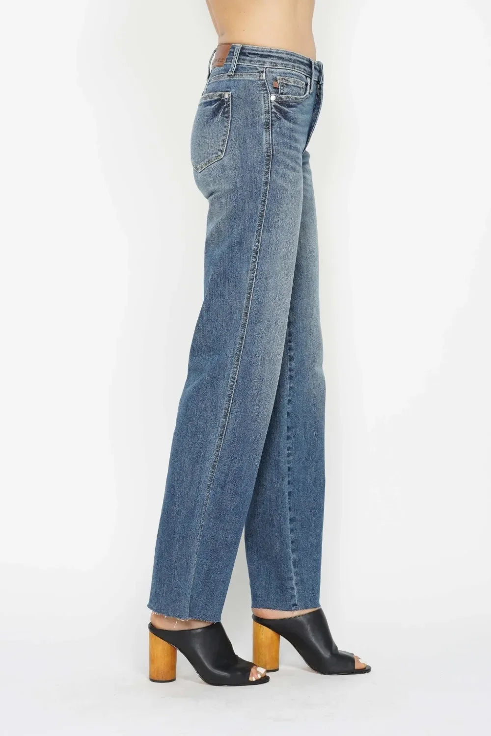 Side view of woman wearing high-waisted straight-leg blue jeans and black heeled mules