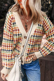 Woman wearing a colorful patterned knit cardigan, blue jeans, layered necklaces, and a cream handbag