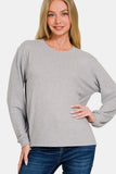 Woman modeling a relaxed fit light grey long sleeve sweatshirt with blue jeans