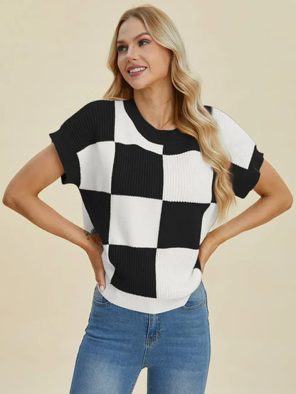 Woman wearing a black and white checkered knit sweater top with short sleeves and blue jeans