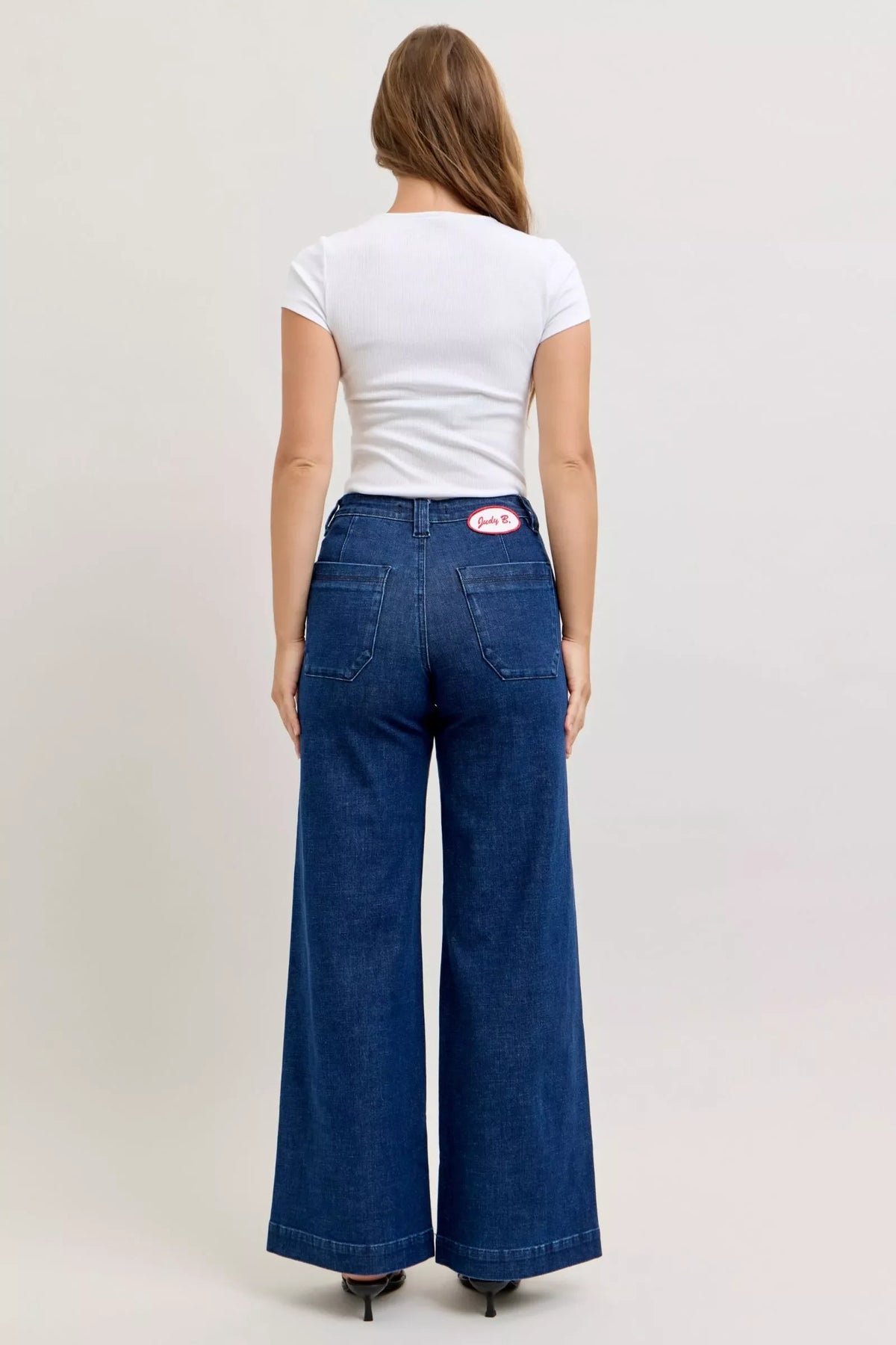 Woman wearing wide-leg high-waisted blue jeans and a white short sleeve top, back view