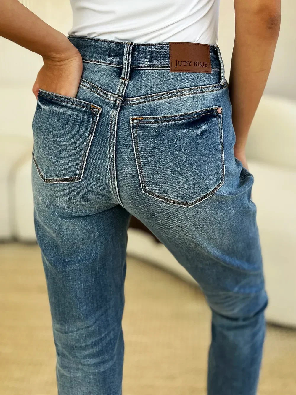 Close-up of woman in high-waisted blue denim jeans with back pockets and white top