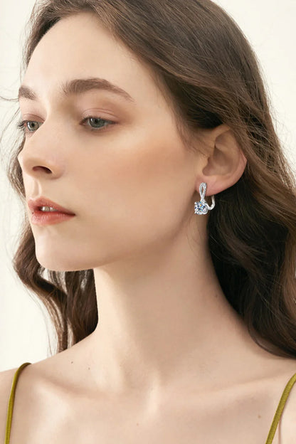 Woman wearing elegant silver drop earrings with crystal detail, neutral background