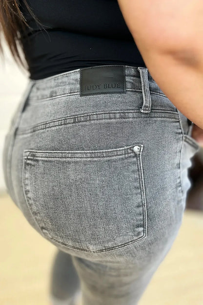Close-up of gray high-waisted jeans with back pocket and black label, worn by a woman.