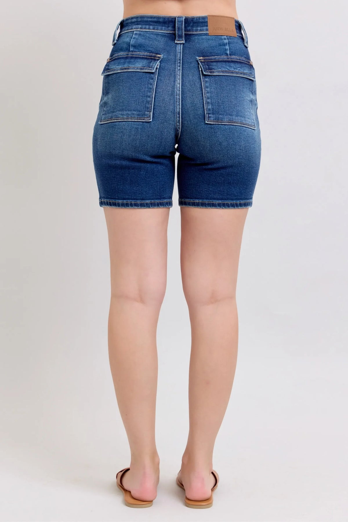Back view of high-waisted denim shorts with patch pockets and relaxed fit on model