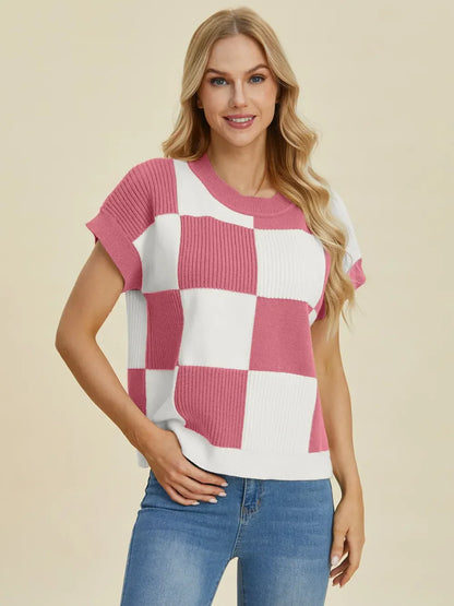 Woman wearing a pink and white checkered knit short sleeve sweater with blue jeans