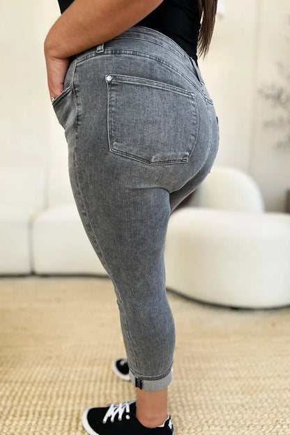 Side view of woman wearing grey cropped skinny jeans with pockets and black sneakers