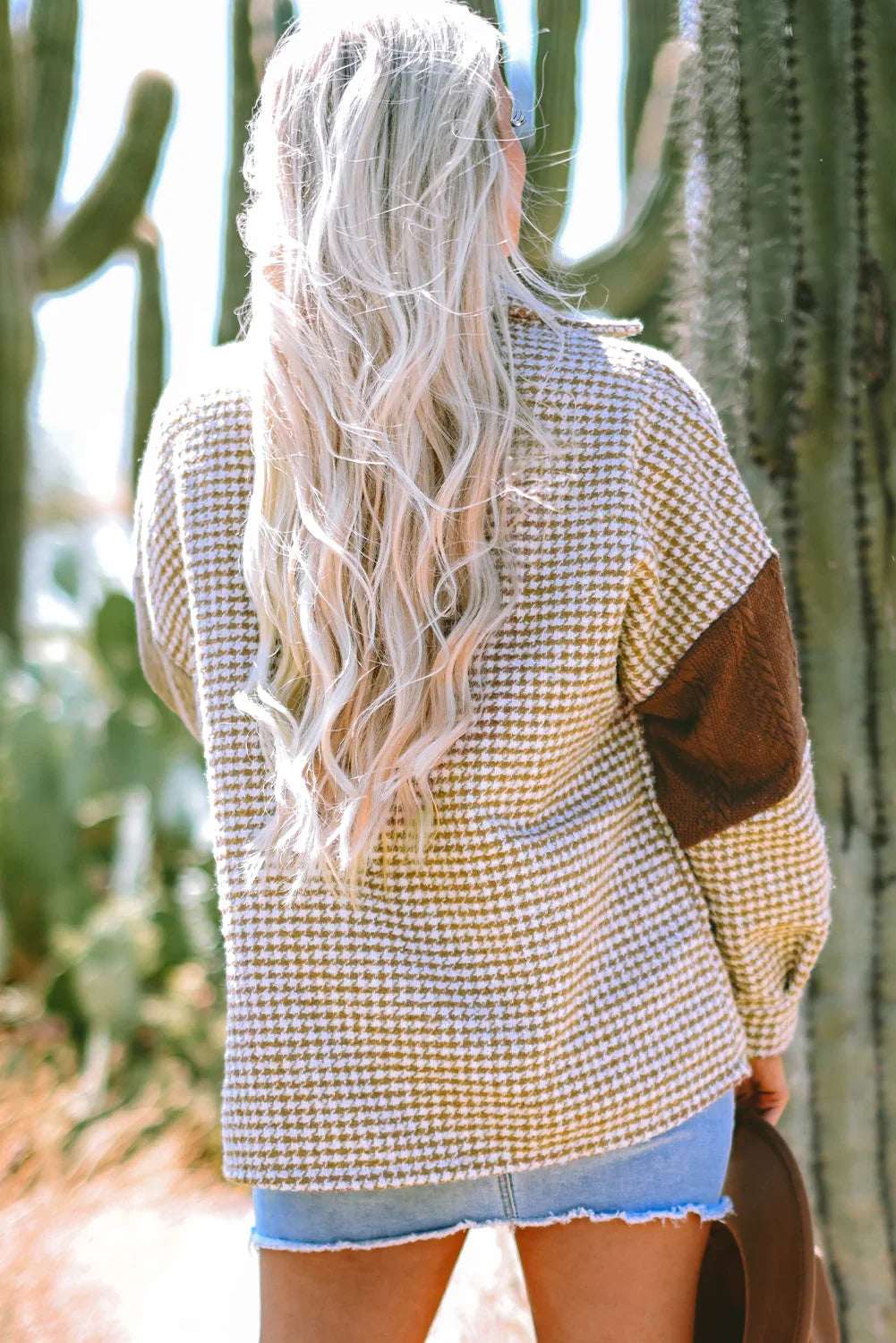 Woman outdoors in houndstooth sweater with brown elbow patch and denim shorts