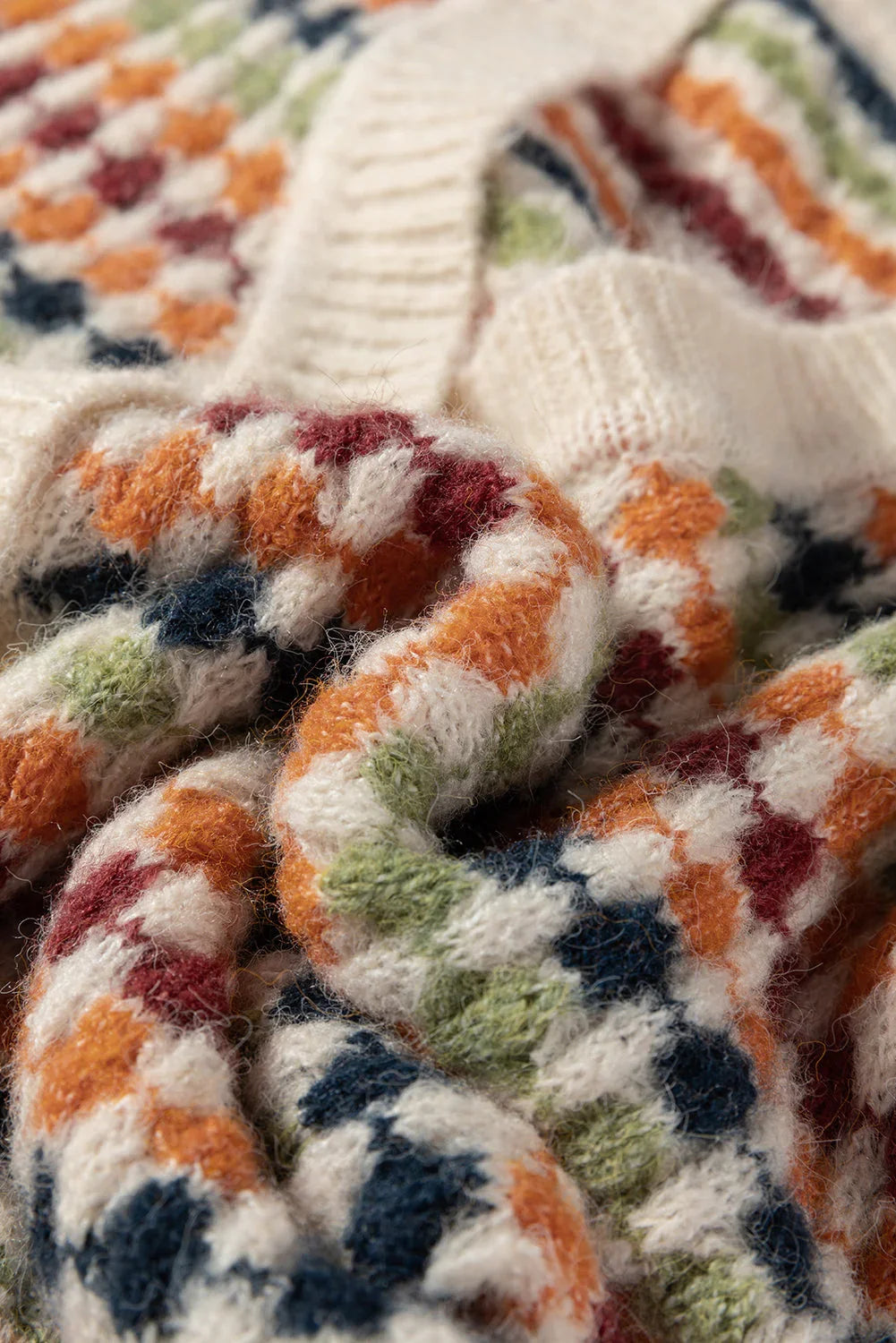 Close-up of soft knit sweater with colorful checkered pattern and ribbed cream collar.