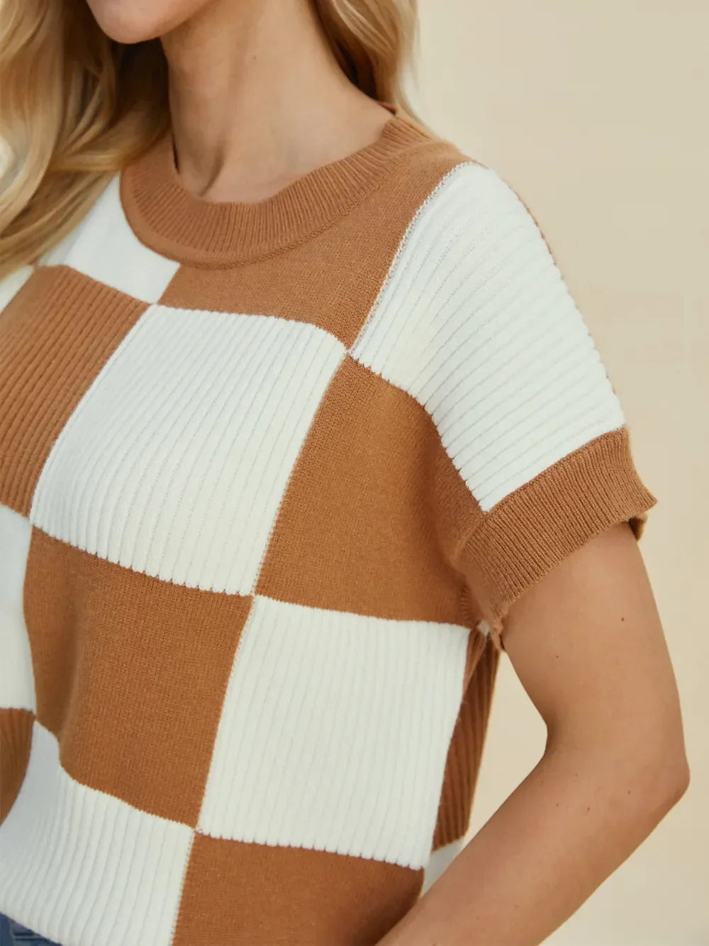Woman wearing a brown and white checkered knit short-sleeve sweater top