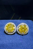Round yellow gemstone stud earrings with diamond halo on blue fabric background