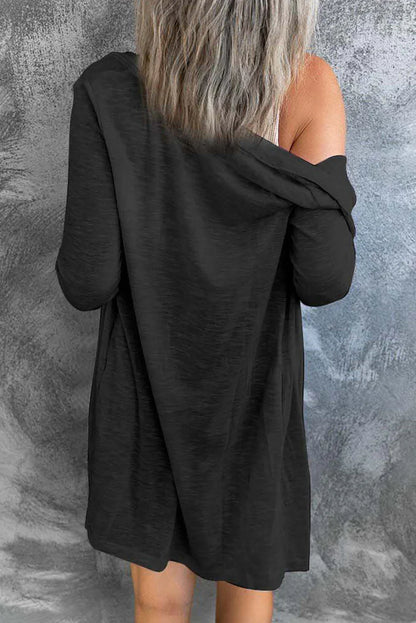 Woman wearing relaxed black long-sleeve dress, off-shoulder, viewed from back