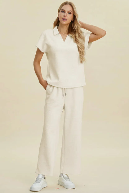 Woman wearing an ivory textured lounge set with short-sleeve collared top and wide-leg pants