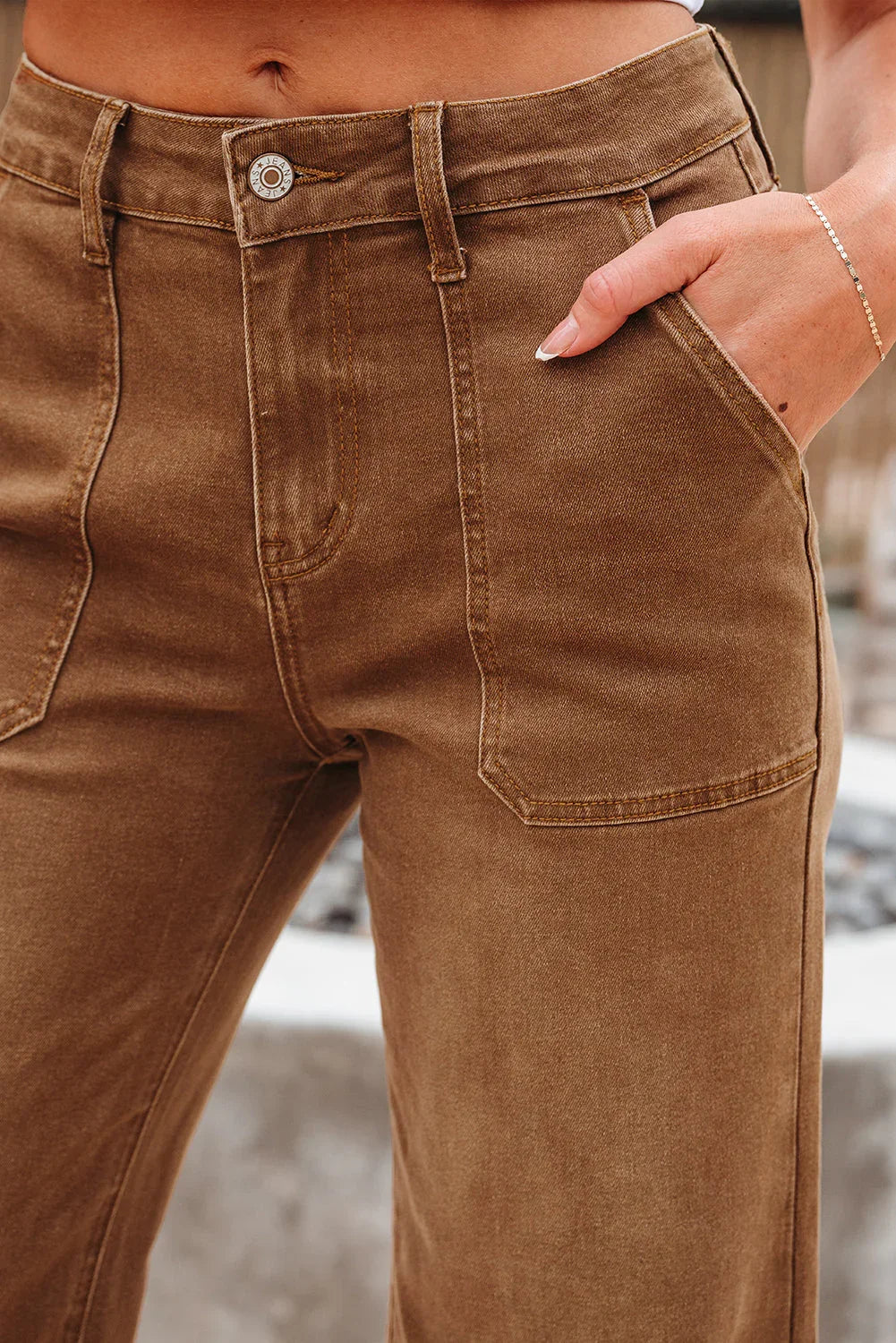 Close-up of high-waisted brown denim pants with front patch pockets and belt loops