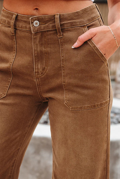 Close-up of high-waisted brown denim pants with front patch pockets and belt loops