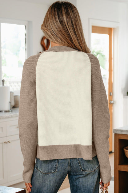 Woman wearing a colorblock knit sweater with taupe sleeves and cream back, paired with jeans