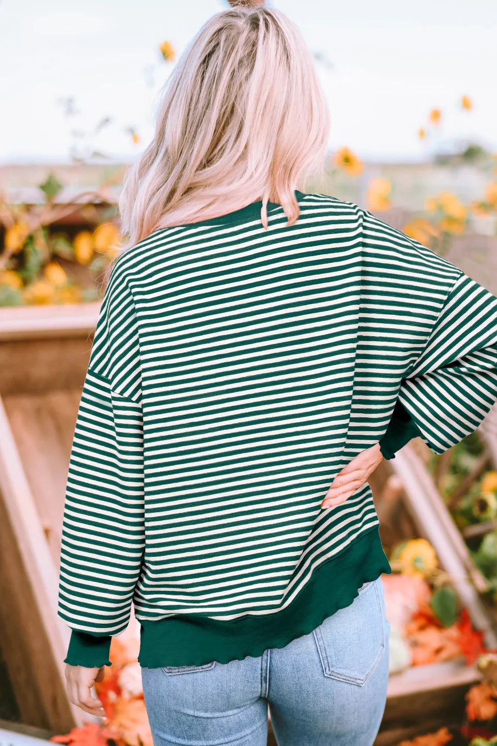 Woman in green and white striped long sleeve top and jeans standing outdoors