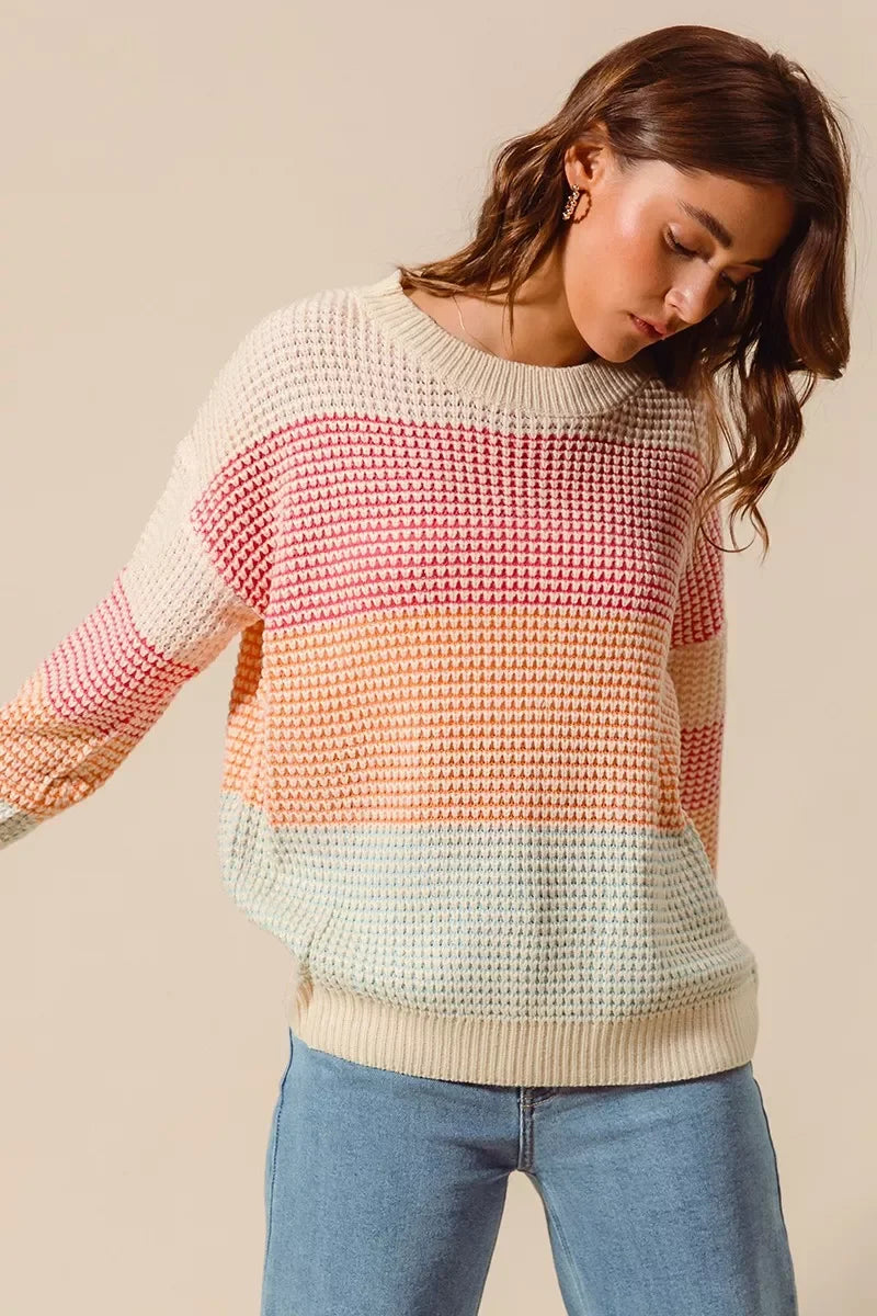 Woman wearing pastel striped knit sweater and light blue jeans, casual fashion