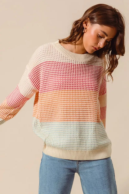 Woman wearing pastel striped knit sweater and light blue jeans, casual fashion