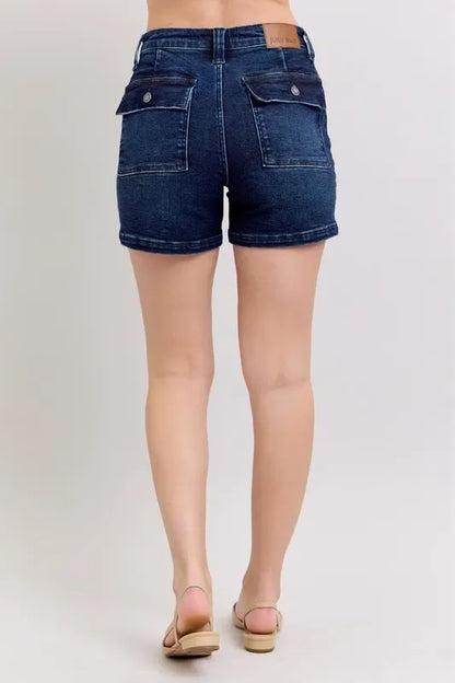 Back view of high-waisted dark wash denim shorts with flap pockets on a model