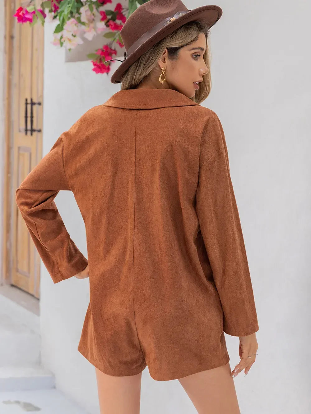 Woman wearing brown suede long sleeve romper and fedora hat, standing outdoors