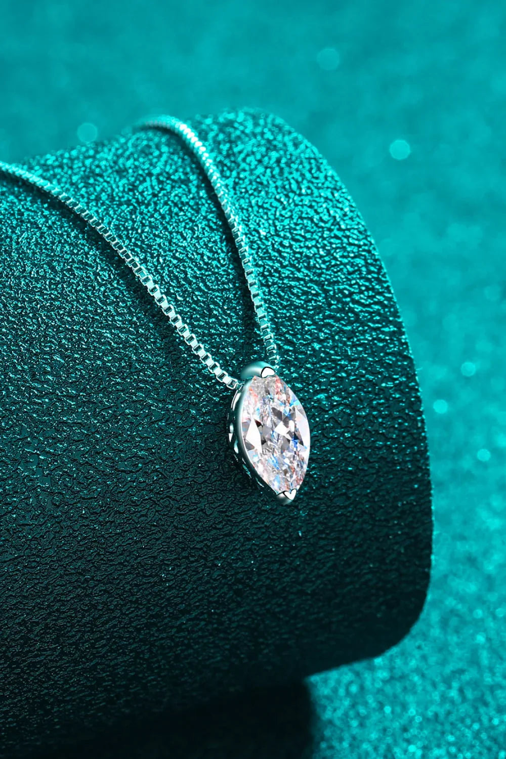 Marquise-cut diamond pendant necklace on a textured teal background