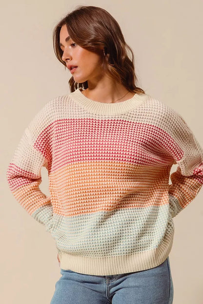 Woman wearing a colorful striped knit sweater with relaxed fit and light blue jeans.