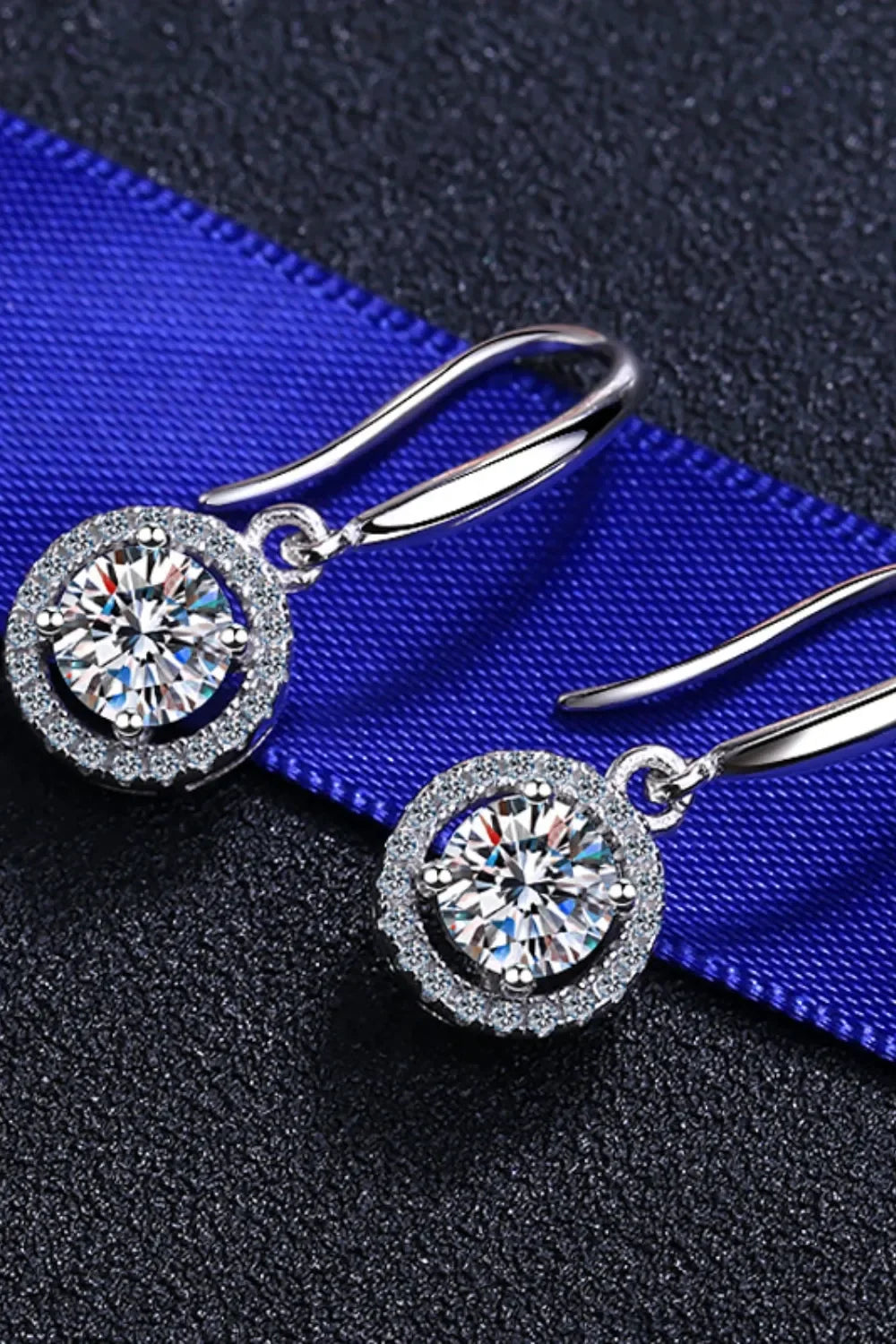 Silver drop earrings with round clear crystals on textured black and blue background