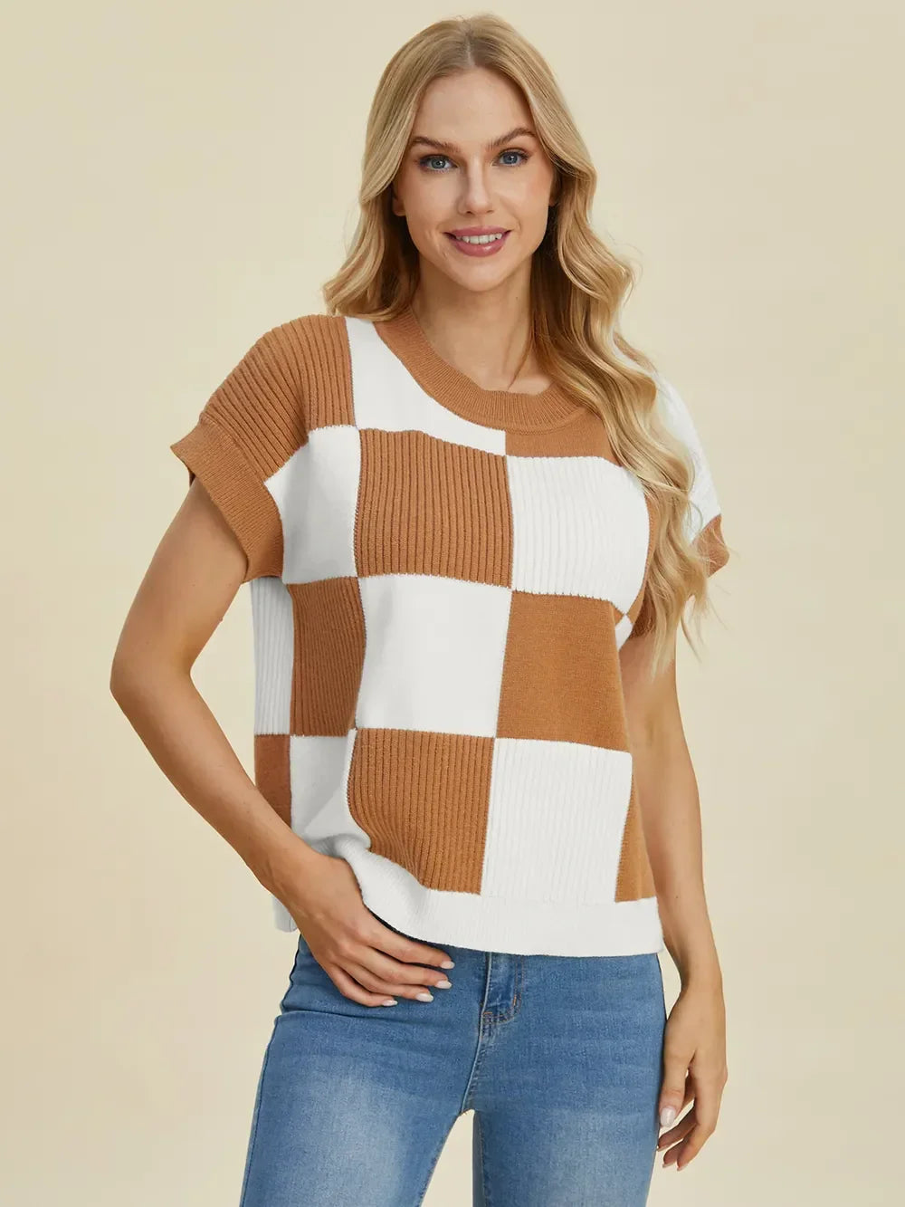 Woman wearing a brown and white checkered knit short sleeve sweater and blue jeans