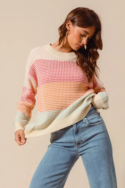 Woman wearing pastel colorblock knit sweater and light blue high-waisted jeans