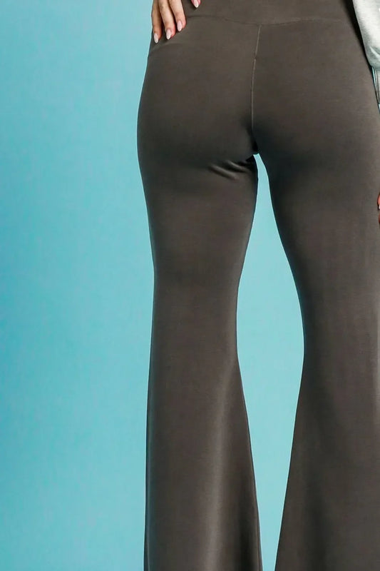 High-waisted taupe flared pants with relaxed fit on model against blue background