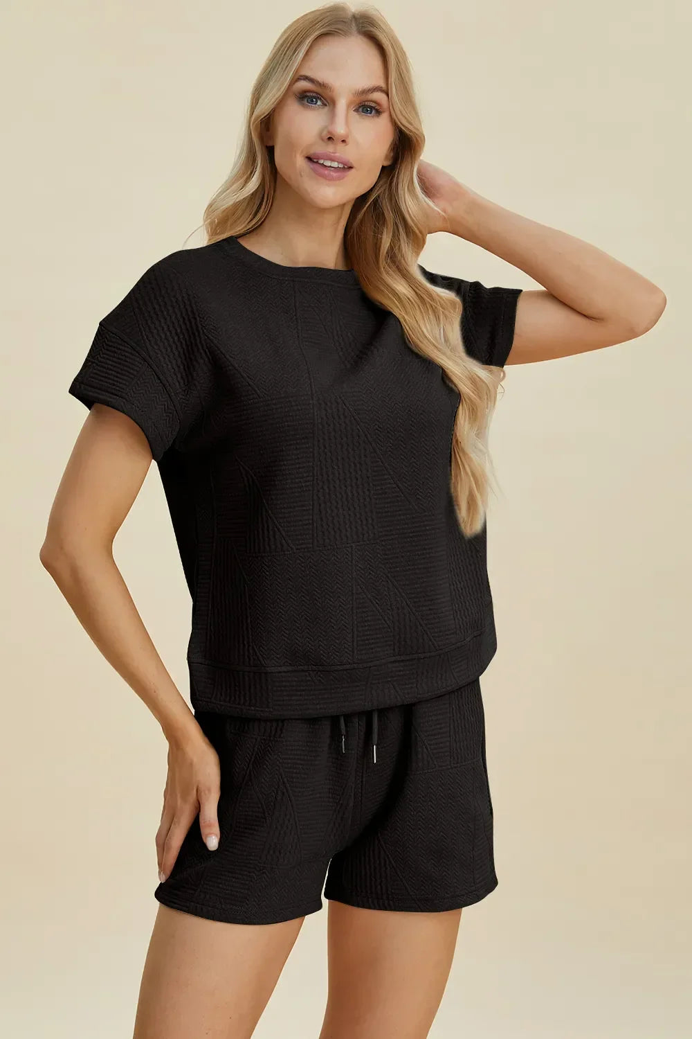 Woman wearing a textured black short sleeve top and matching black shorts set