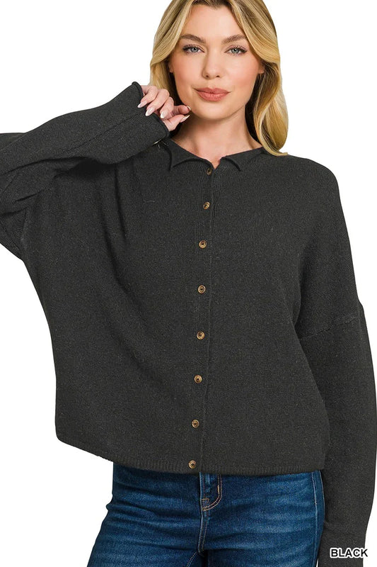 Woman wearing a black button-up knit cardigan with long sleeves and blue jeans