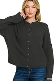 Woman wearing a black button-up knit cardigan with long sleeves and blue jeans