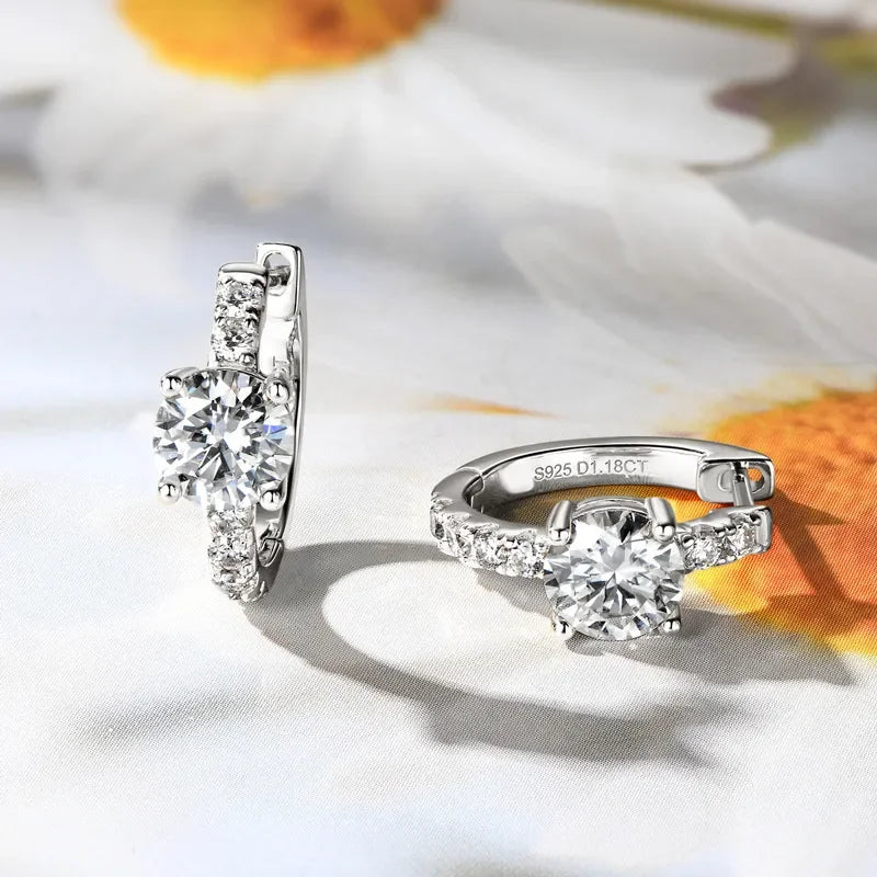 Pair of silver hoops with round-cut cubic zirconia stones on a floral background