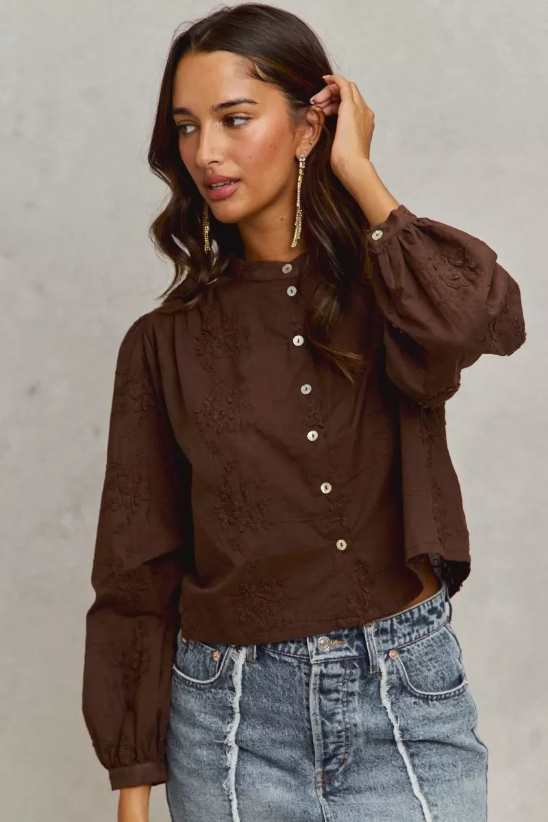 Woman wearing a brown embroidered blouse with balloon sleeves and blue distressed jeans