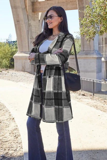 Woman outdoors wearing black and white plaid coat, flared jeans, sunglasses, and crossbody bag