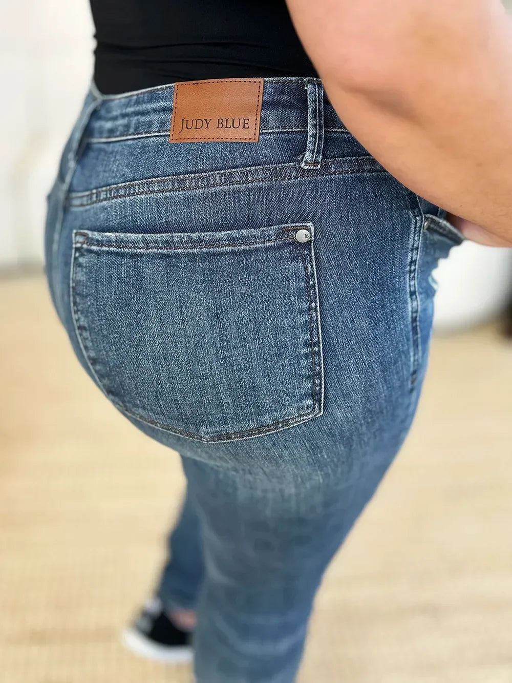 Close-up of Judy Blue high-waisted blue denim jeans with back pocket and leather patch.