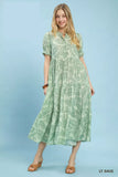 Woman wearing an Umgee Paisley Print Tiered Midi Dress on a blue background and brown slip on heeled sandals