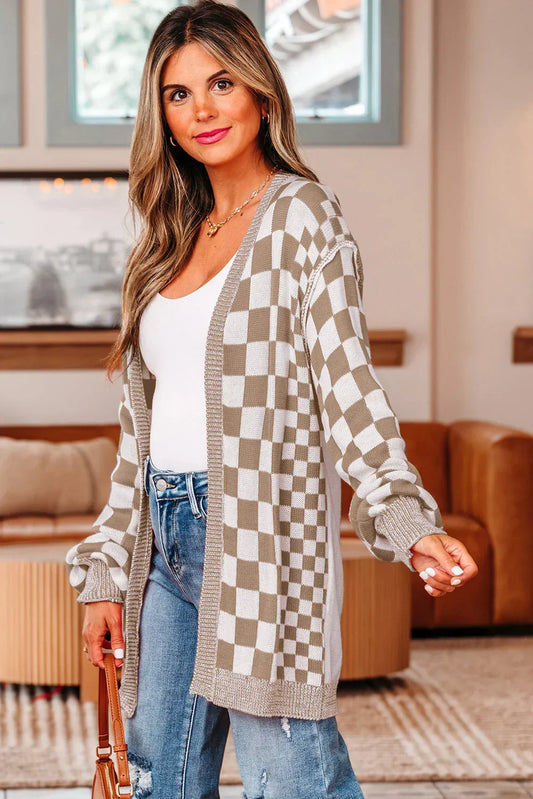 Woman wearing taupe checkered cardigan, white tank top, and distressed jeans in modern living room