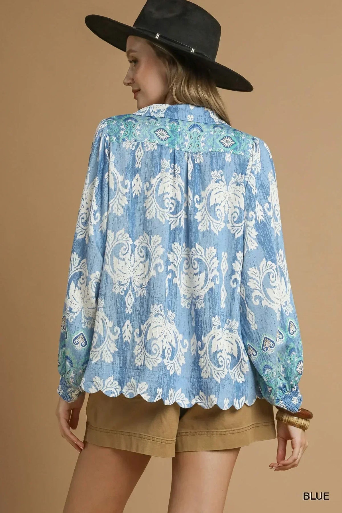 Woman wearing blue floral long-sleeve blouse with scalloped hem and tan shorts
