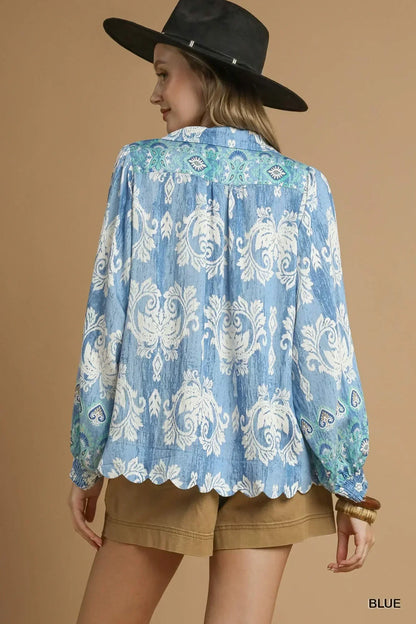 Woman wearing blue floral long-sleeve blouse with scalloped hem and tan shorts