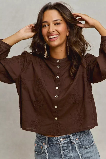 Woman wearing a dark brown button-up embroidered blouse with relaxed fit and blue denim jeans