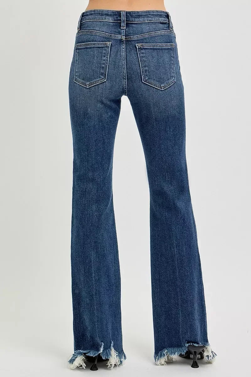 Back view of high-rise flared blue jeans with raw frayed hems on a white background.