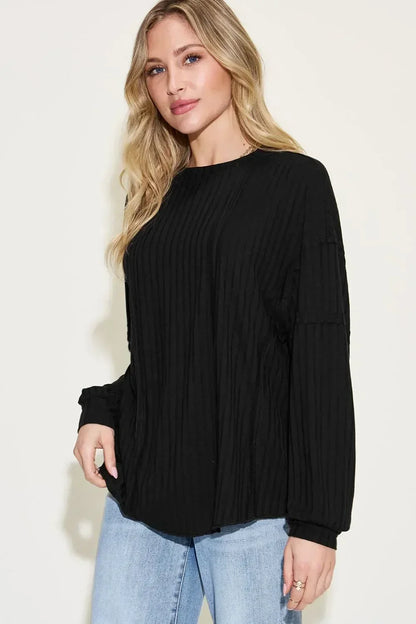 Woman wearing a black ribbed long sleeve sweater with relaxed fit and light blue jeans